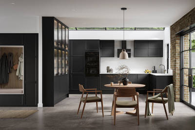 Modern Shaker kitchen Brunswick Sumi Black handleless with integrated ovens in tall cabinetry, open layout living room with wood dining table, hallway cabinetry with coat hangers and akupanel.