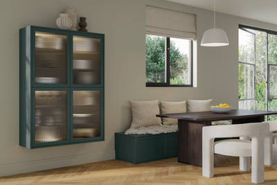 Seating area in muted green modern shaker Brunswick kitchen, a green bench with woft white pillows and wall cabinetry with fluted glass fronts.