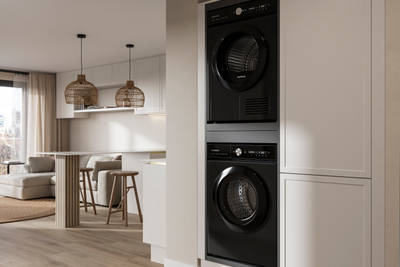 View from utility room with integrated washing machine and tumble dryer of handleless Wabi sabi inspired Integra Brunswick Limestone kitchen combined with living area, wood barstools for breakfast bar, natural materials, Euros oak flooring.