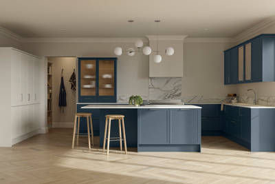 Modern Shaker kitchen Brunswick Voyage blue and Limestone with white and grey marbled worktop and matching splashback, a kitchen island with light wood stools at breakfast bar and vitrine cabinets with fluted glass, light wood herringbone flooring.
