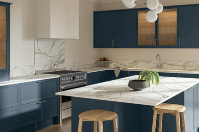 View over kitchen island breakfast bar in modern Shaker kitchen Brunswick Voyage blue with white and grey marbled worktop and matching splashback, and vitrine cabinets with fluted glass.