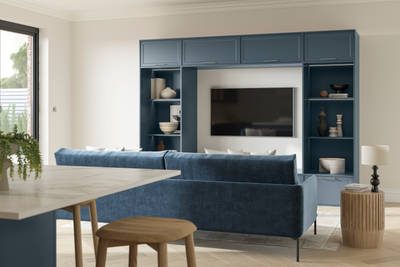 Cabinets and open shelves around a wall mounted TV in the modern Shaker range Brunswick Voyage Blue, matching blue counch and kitchen island in the foreground.