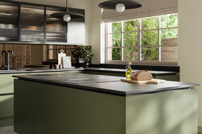 View over kitchen island in Integra Soho Tailored Green cabinetry, with Dekton worktop, fluted glass vitrine wall cabinets and large windows.