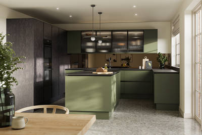 Integra Soho Tailored Green kitchen and kitchen island with contrasting dark wood Portobello Etna, black accessories, integrated ovens in tall cabinets, Dekton worktop and fluted glass vitrin wall cabinets with wood dining room table in foreground.