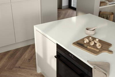 View of wood cutting board and knife with mushrooms on Minerva chalk venato worktop covered contemporary Luna Gloss Limestone kitchen island with integrated oven, Amtico smouldering oak parquet flooring.