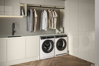 Contemporrary and elegant Luna Gloss Limestone kitchen with integrated washing machine and tumble dryer, tall cabinets, coat hanger under top cabinets and a black sink matched with black tap and Amtico smouldering oak parquet flooring.