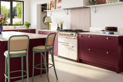 Modern slab front Soho Morello kitchen. kitchen island with rattan bar stools at breakfast bar, Bianco calacatta worktop and upstand, brass knobs and Otto tiles dirty pink stripes as splashback behind range cooker.