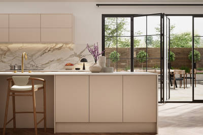 Fluted front kitchen Reed from Magnet in light warm neutral shade Shell, with a marbled splashback, worktop and decorative side on kitchen island with barstools and black handles, herringbone wood flooring.