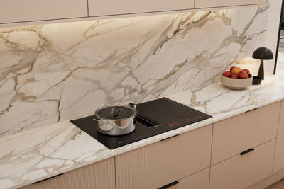 Fluted front kitchen Reed from Magnet in light warm neutral shade Shell, with a marbled splashback and worktop, induction hob and black handles