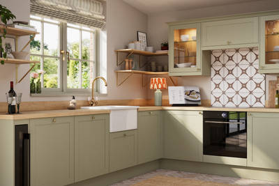 Close-up view of contemporary Shaker kitchen Ambleside from Magnet in sage green shade Meadow with belfast sink, aged taps and wooden effect worktop.