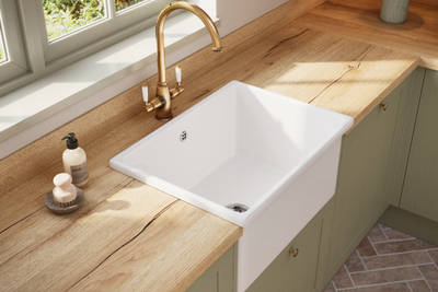 White ceramic Belfast sink and traditional style hot water tap in Contemporary Shaker kitchen Ambleside from Magnet in sage green shade Meadow with wooden effect worktop.