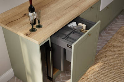 Contemporary Shaker kitchen Ambleside from Magnet in sage green shade Meadow with integrated recycling bins and wooden effect worktop.