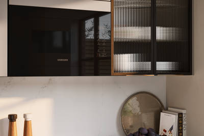 Close-up view of fluted glass vitrine in modern slab front Soho Cornish Clay kitchen from Magnet in Pantone’s colour of the year ‘Mocha Mousse’ with bronze trim handles, handles, silestone quartz worktop and matching backsplash.
