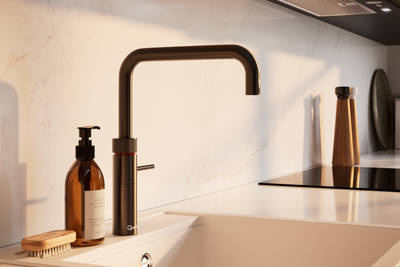 Close-up view of Quooker Fusion square 4in1 tap with boiling water in modern slab front Soho Cornish Clay kitchen from Magnet in Pantone’s colour of the year ‘Mocha Mousse’ with silestone quartz worktop and matching backsplash.
