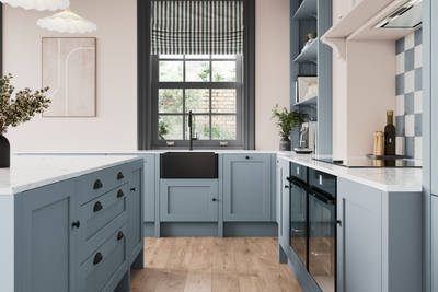 Parallell view of premium Shaker kitchen Wardley Portland Blue including kitchen island with traditional detailing, black accessories, white worktop and matching blue open shelves with blue panelling and checkered tiling over range cooker.