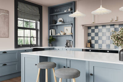 Close-up view over kitchen island in premium Shaker kitchen Wardley Portland Blue with traditional detailing, black accessories, white worktop and matching blue open shelves with blue panelling.