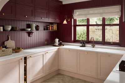 Painted wood grain Shaker style Bewdley kitchen with cabinets in light pink shade Chalk Blush, marbled worktop, brass knobs, red Morello wall-mounted cabinets with matching shelves and wall panel, built- in wine storage.