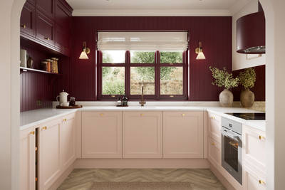 Painted wood grain Shaker style Bewdley kitchen with cabinets in light pink shade Chalk Blush, marbled worktop, brass knobs, red Morello wall-mounted cabinets with matching shelves and wall panel, built- in wine storage.