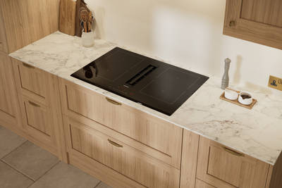 View of vented hob and marbled worktop in Traditional premium contemporary Shaker kitchen Ambleside in oak with brass knobs and handles.