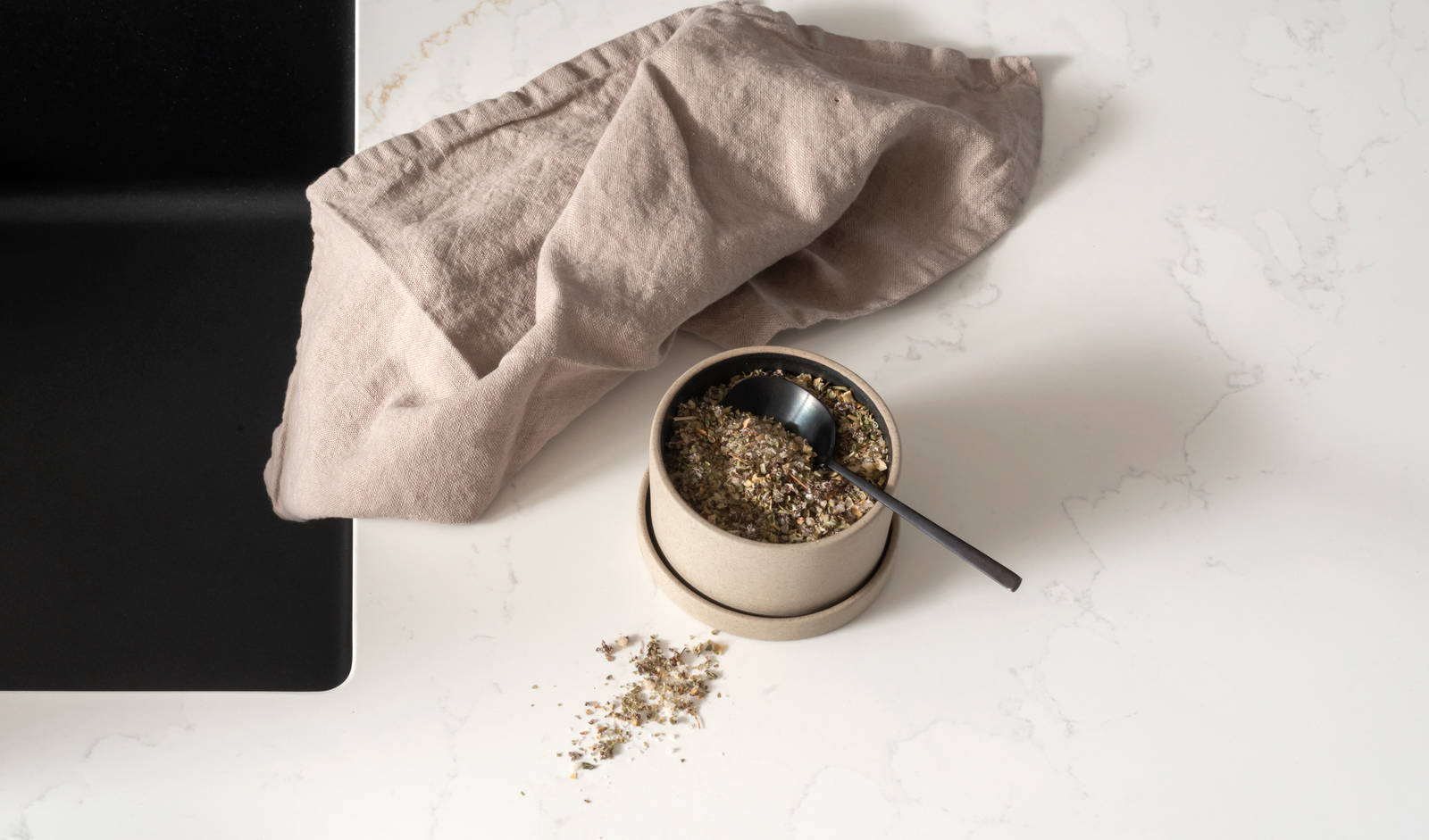 Et nydelig svart kjøkken i lun eik med kjøkkenøy dekket av lys komposittstein og stilige matt-svarte håndtak.