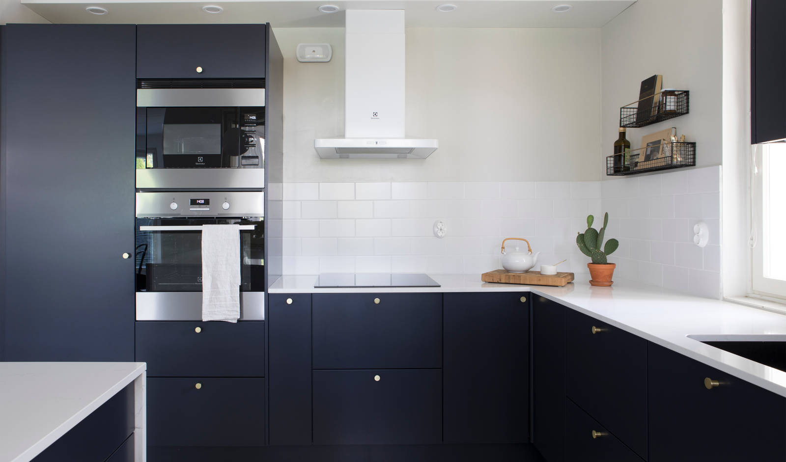 Tummansiniseksi Meri maalattu sileä keittiö, jossa valkoinen marmoroitu työtaso ja yhteensopivat splashback, messinkinupit