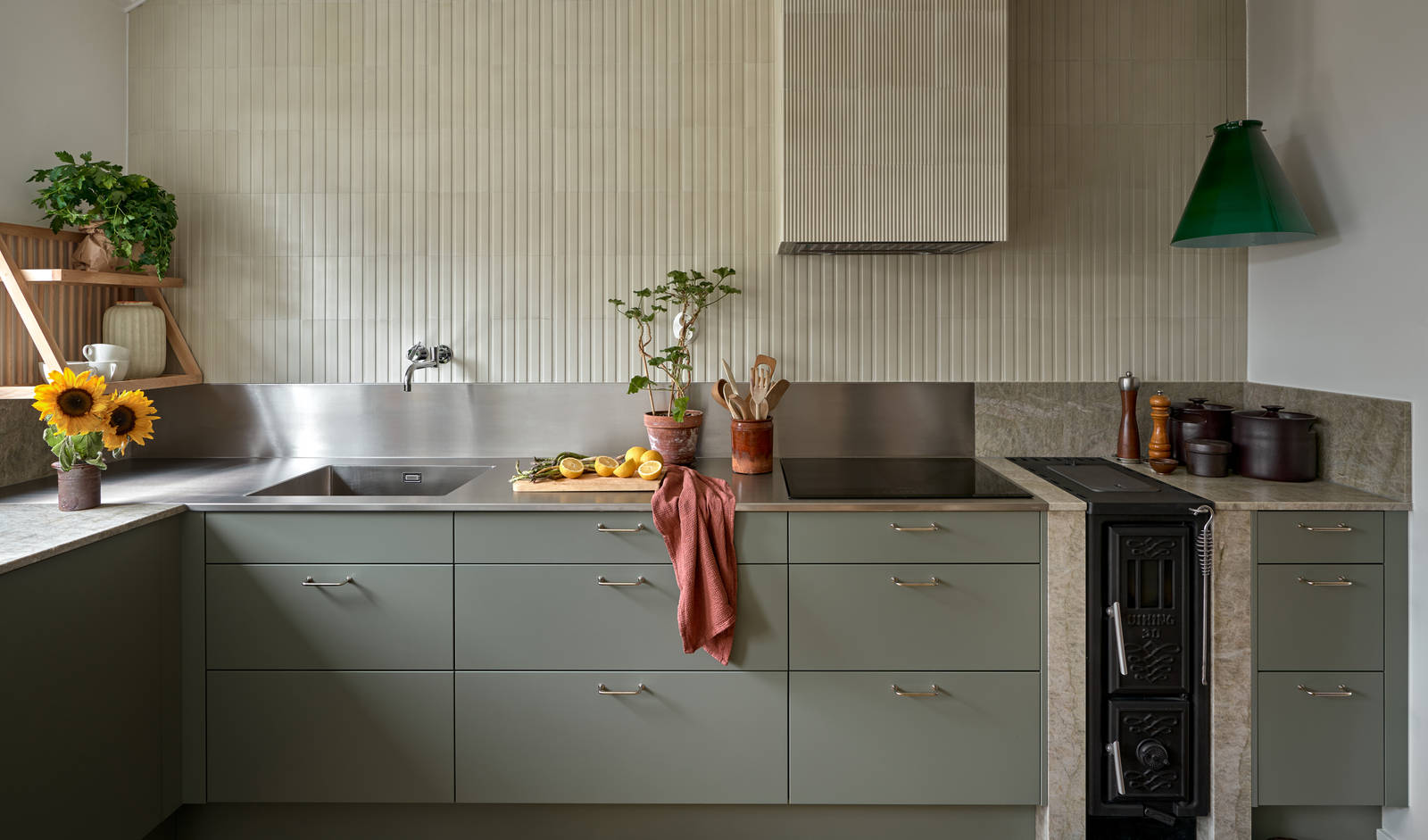 Inredningsprofilen Svante Öquists kök från Marbodal, Arkitekt Plus i den gröna kulören Tall med rostfri bänkskiva i kombination med kvartsit, handtag i krom. Vedspis och induktionshäll.