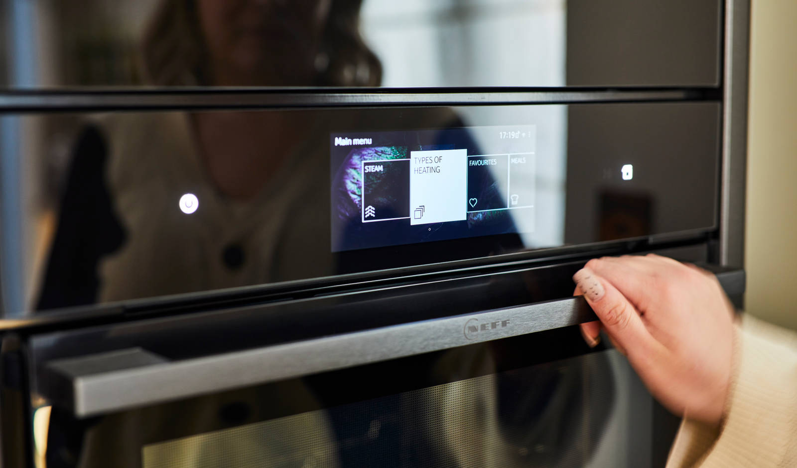 Close-up of hand on oven handle, focusing on the digital display