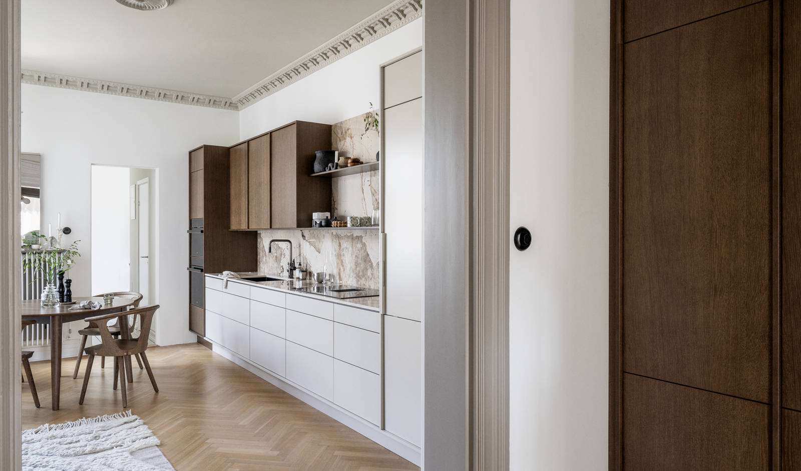 Kjøkken med kombinasjon av kjøkkenbenk i beige Line Korn med overskap i Signature Favn, finert eikedør i brunbeiset Nøtt fra Sigdal, matchende benkeplate og sprutbak, og åpne vegghyller i brunbeiset eikefiner.