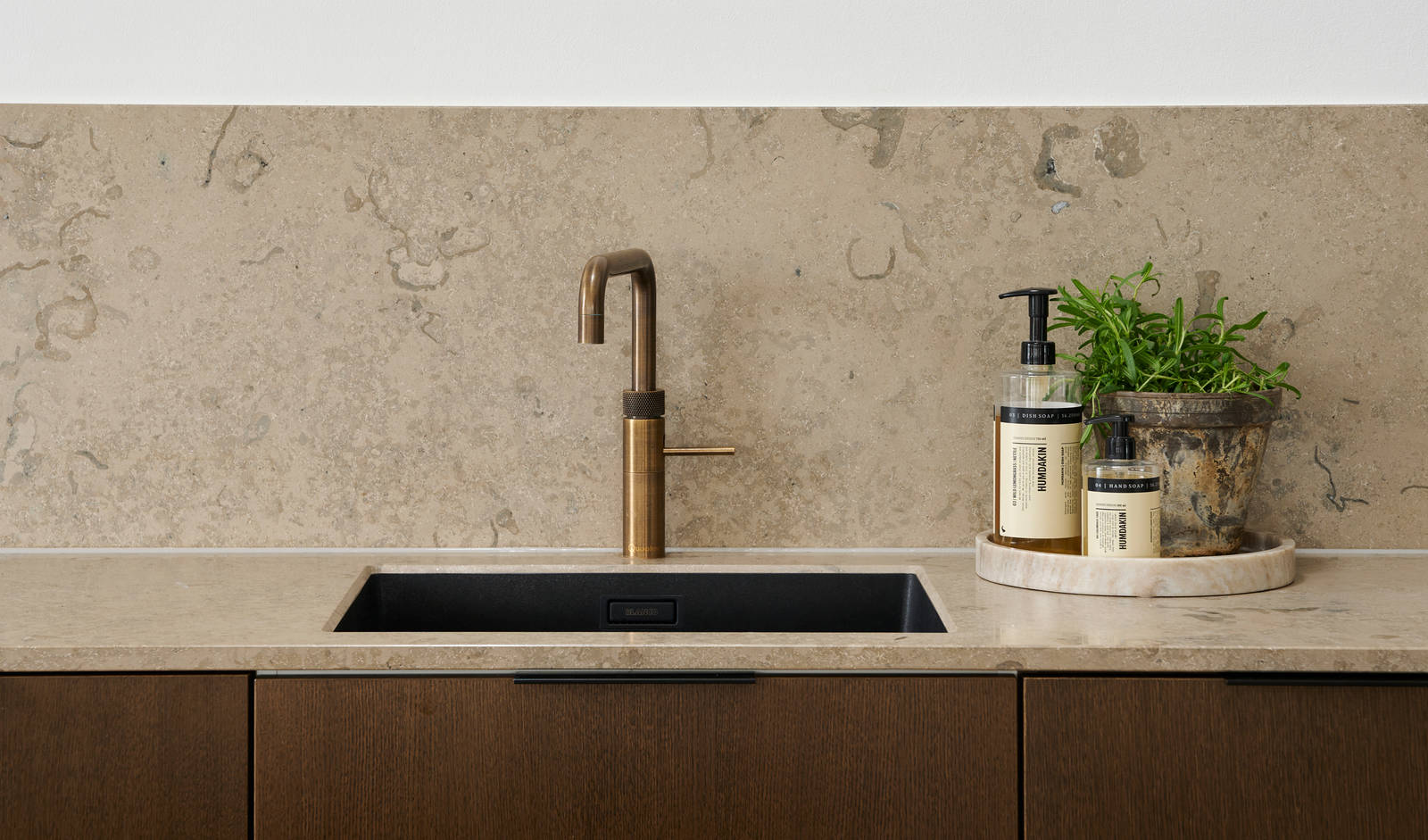 Forever Oak køkken med mørke træ fronter, marmor bordplade og splashback, sort vask og messing armatur