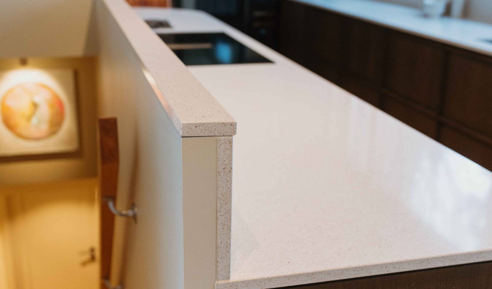 Eikekjøkkenet Favn fra Sigdal i beisfargen Nøtt, matchende tre håndtag, med benkeplate Blanco City fra Silestone og sort vask og sort blandebatteri.