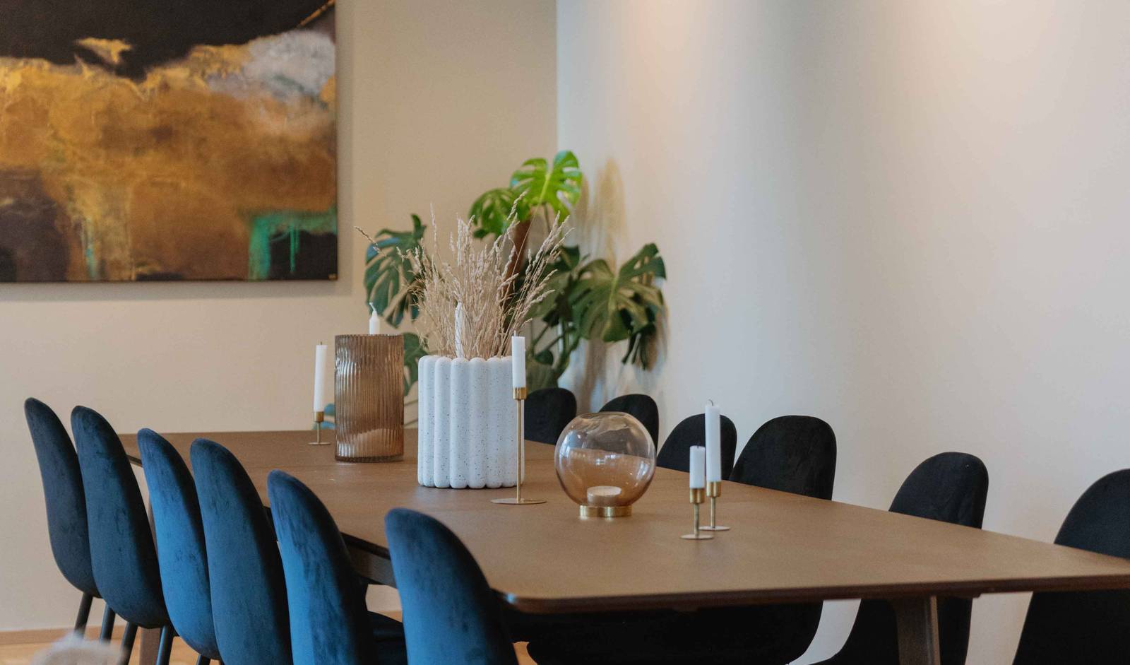 Spisestue med langbord i mørkt træ, dekoreret med messing lysestager