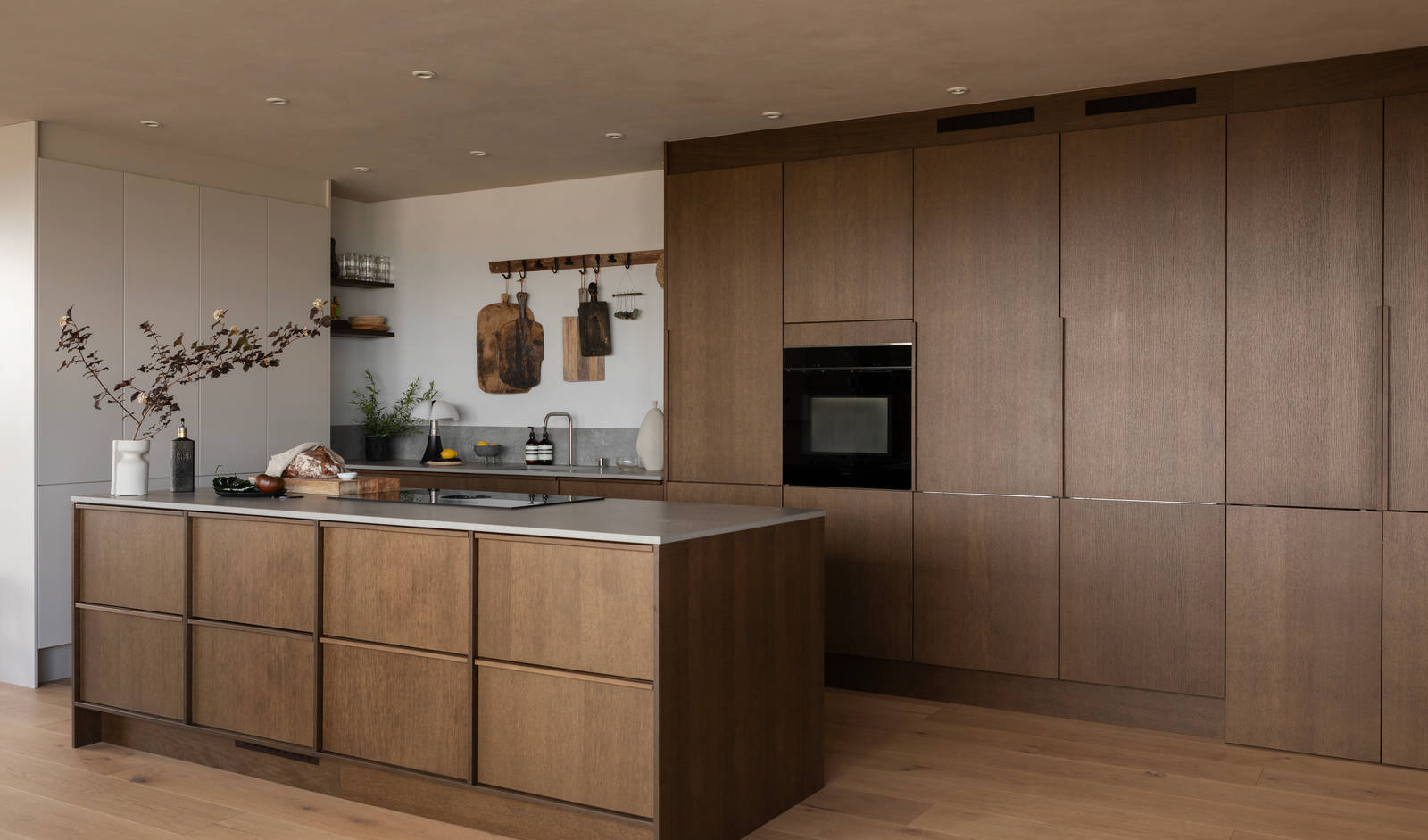 Køkkenø i brun egetræsfiner køkkenet Forever oak med matchende tre håndtag fra INVITA og beige højskabe Athena Sand