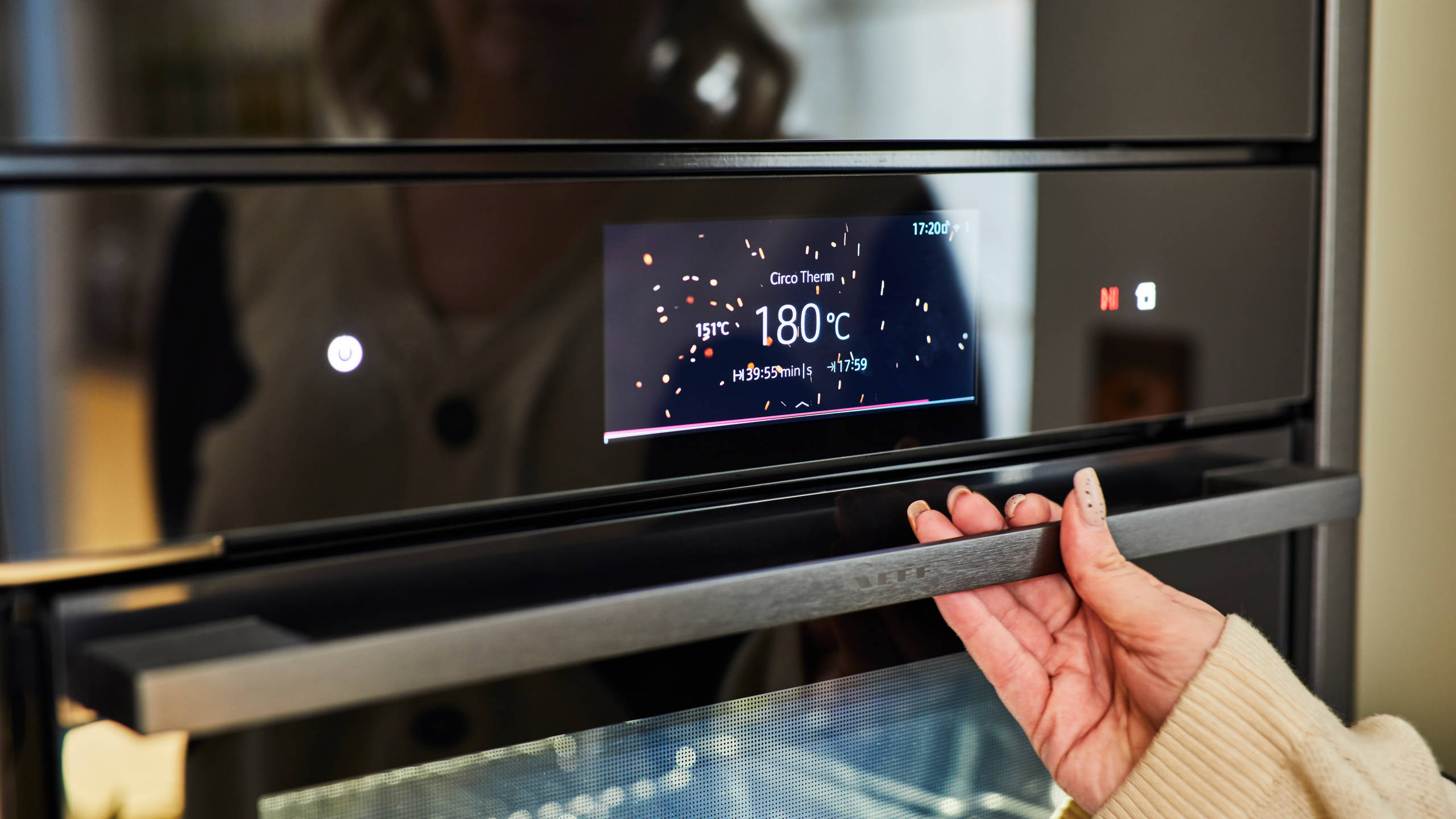 Close-up of Jen's hand on the oven handle as the display says 180 degrees celsius.