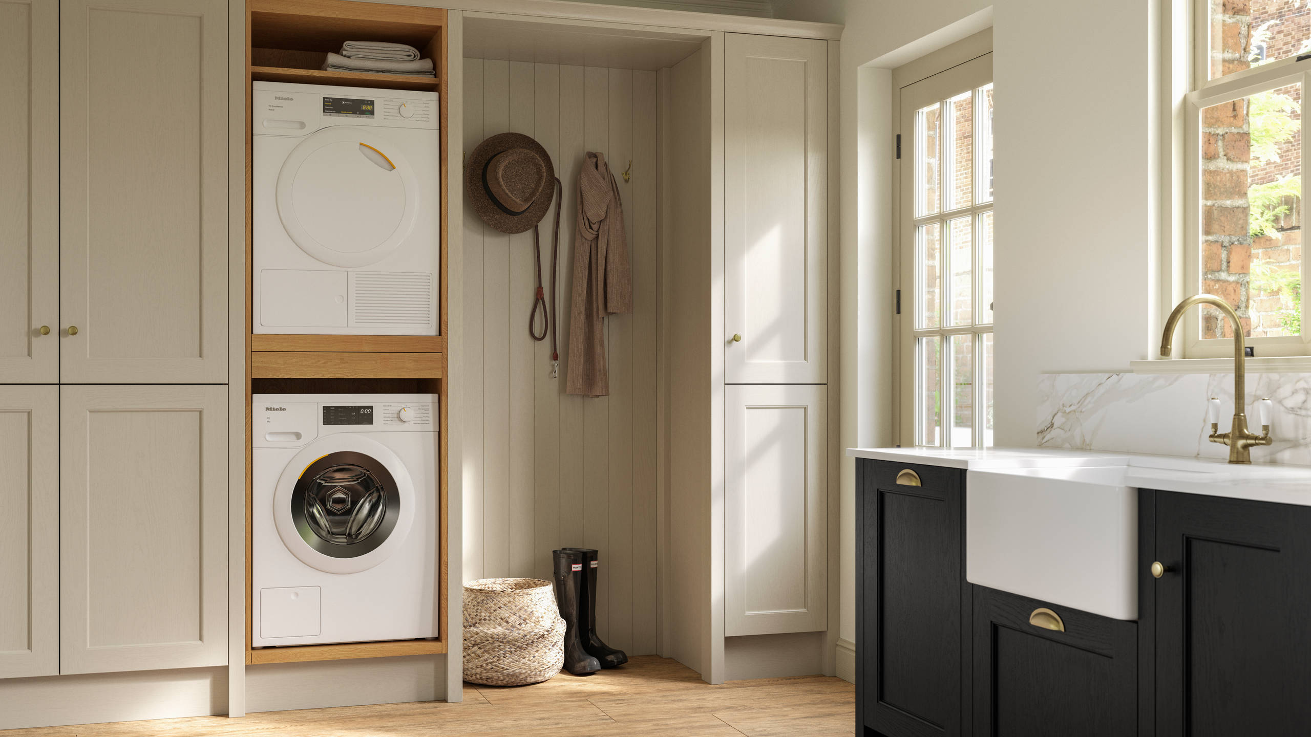Utility room with Traditional Shaker-style tactile woodgrain Ludlow French Clay cabinets, washing machine and tumble dryer, Ludlow Sumi Black kitchen with brass accessories, Amtico oak stripwood vinyl flooring.