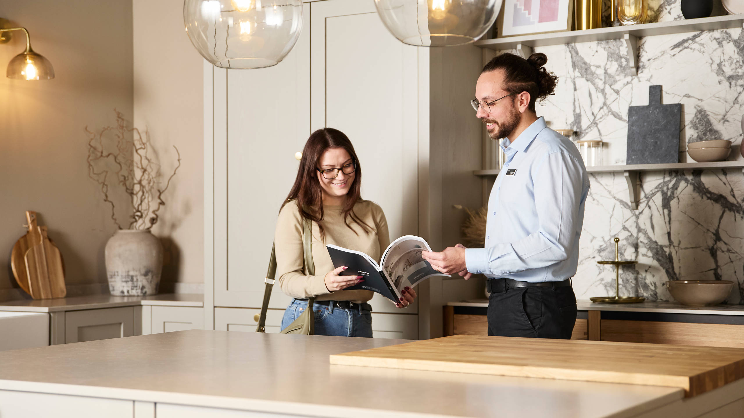 Woman and kitchen designer looking at and discussing a brochure in Shaker style kitchen at a Magnet Showroom.