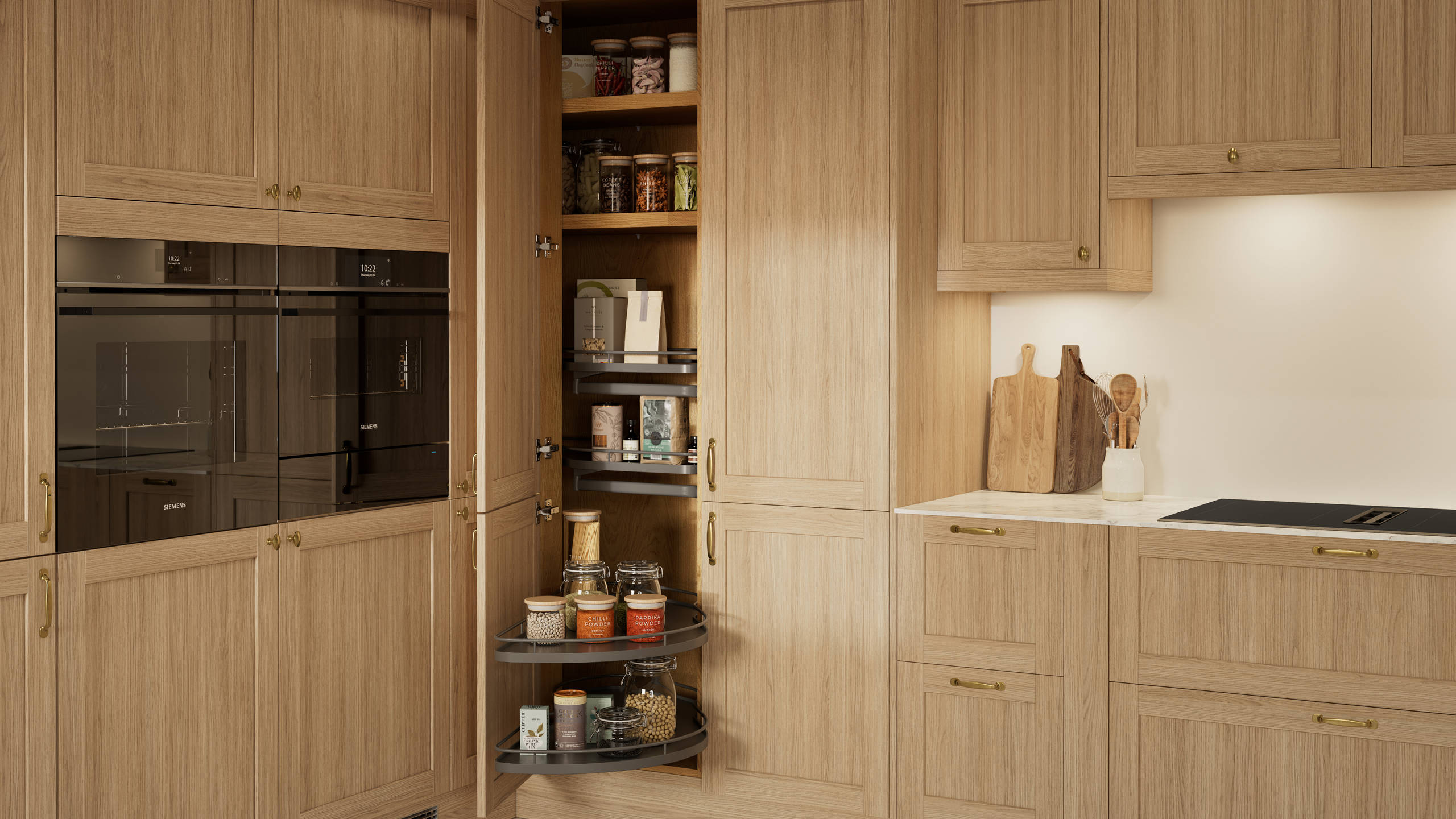 Traditional premium contemporary Shaker kitchen Ambleside in oak with brass knobs and handles, built-in ovens in tall cabinetry, opened tall corner cabinet with oak shelves and pull-out carousel.