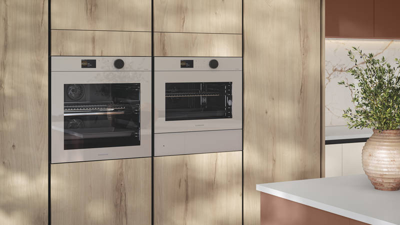 Tall Integra Portobello Bosco cabinetry, a contemporary handleless slab with with organic woodgrain texture, and integrated Samsung ovens.