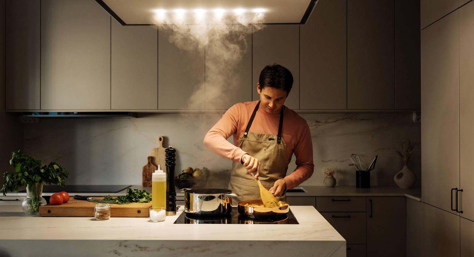 Filip Poon lagar mat i sitt clean och eleganta Arkitekt Plus Sand-kök från Marbodal med Dekton-bänkskiva och matchande stänkskydd