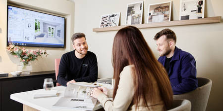 Magnet kitchen designer consulting customers in a Magnet store, woman browsing a brochure.