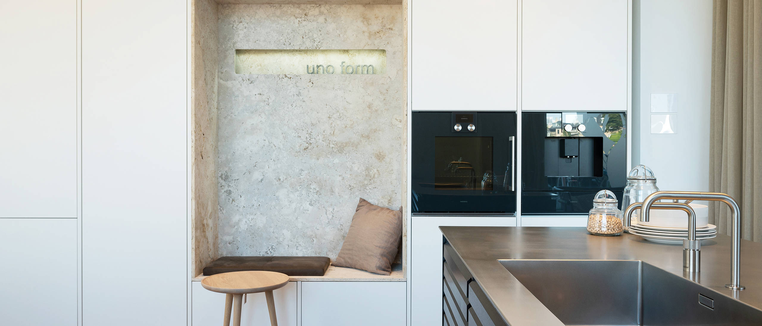 Køkkenø i røget eg med stålbordplade og hvid højskabsvæg med alkove