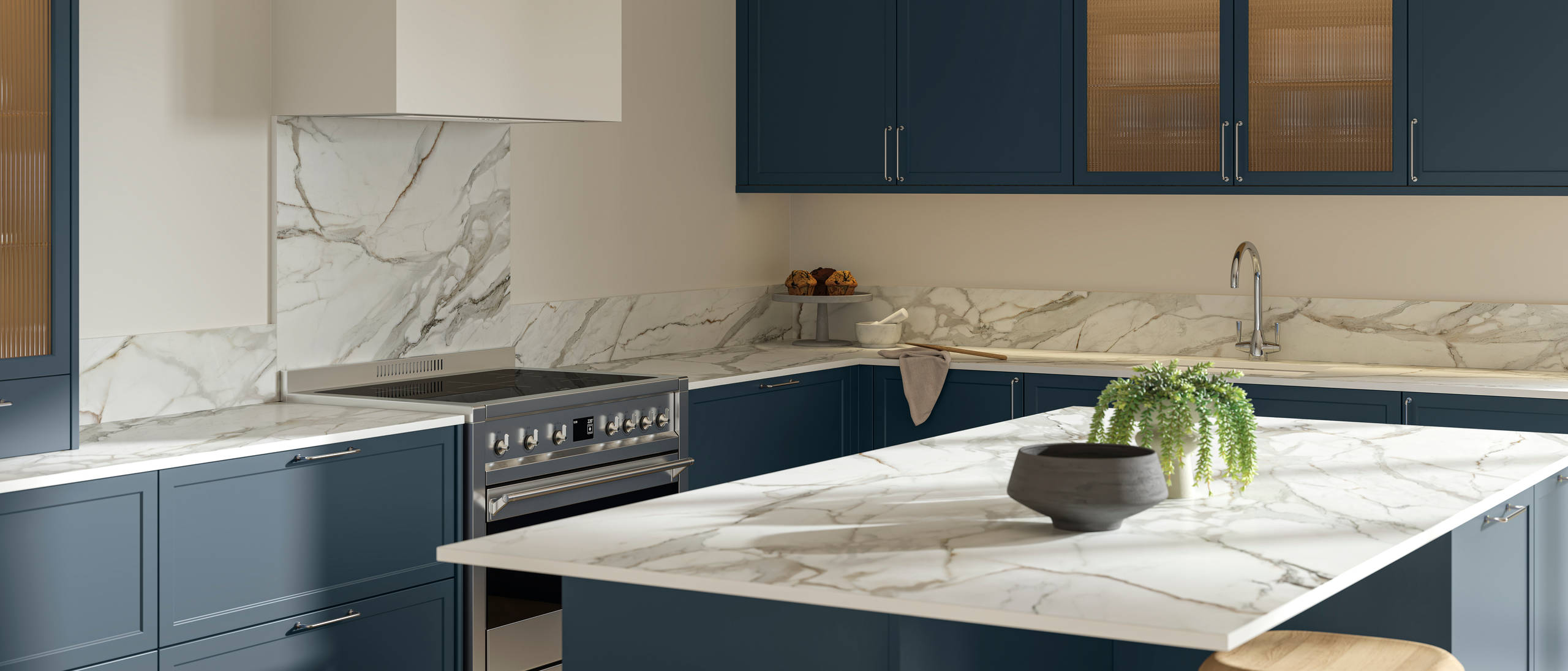 View over kitchen island breakfast bar in modern Shaker kitchen Brunswick Voyage blue with white and grey marbled worktop and matching splashback, and vitrine cabinets with fluted glass.