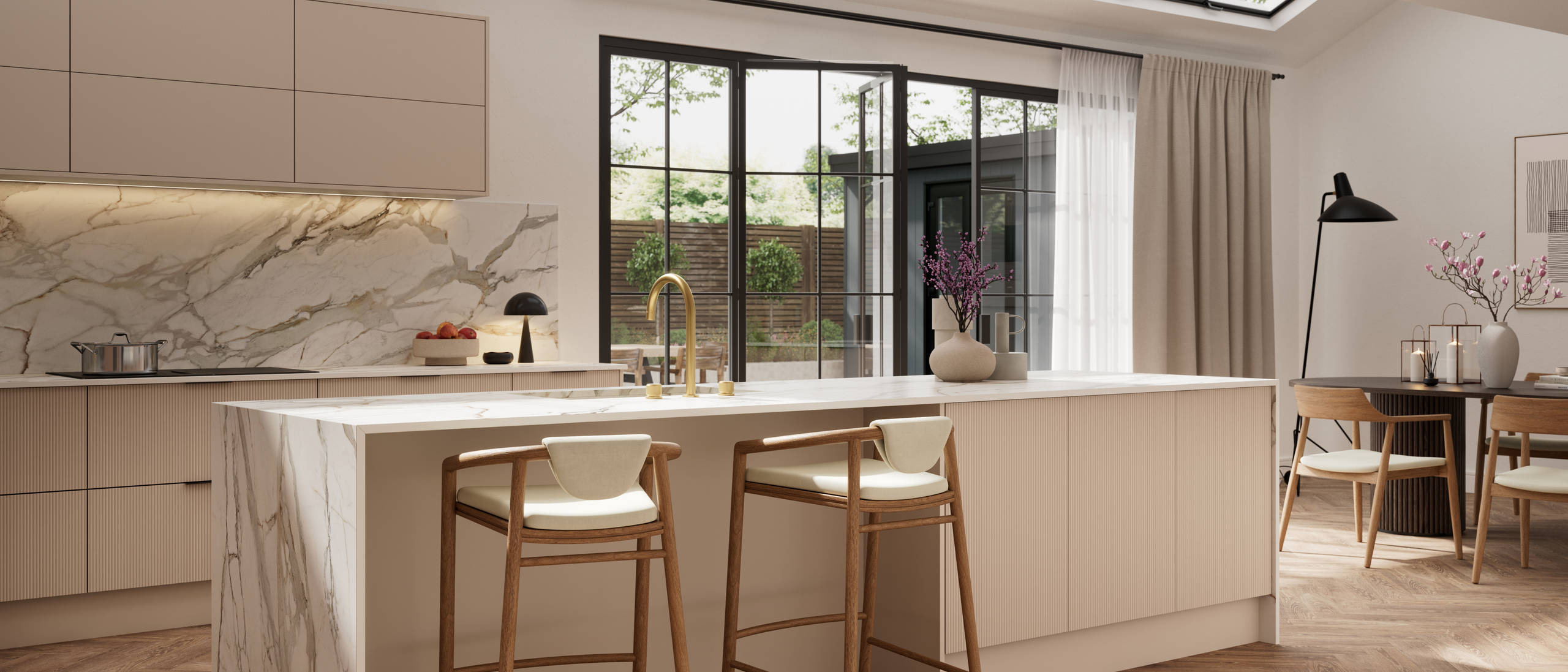 Fluted front kitchen Reed from Magnet in light warm neutral shade Shell, with a marbled splashback, worktop and decorative side on kitchen island with barstools and black handles, herringbone wood flooring.
