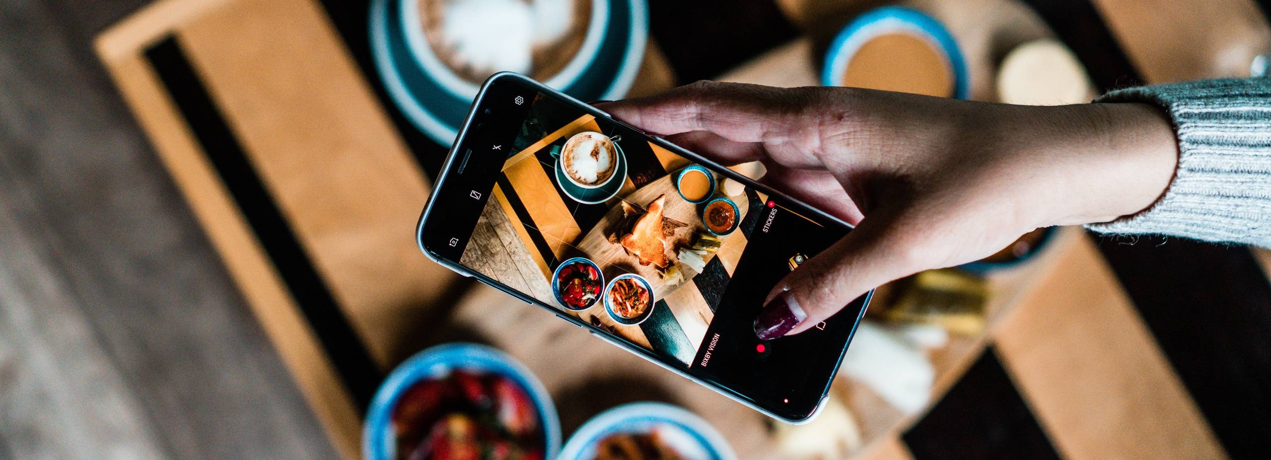 Hand holding smartphone taking a picture of plated food