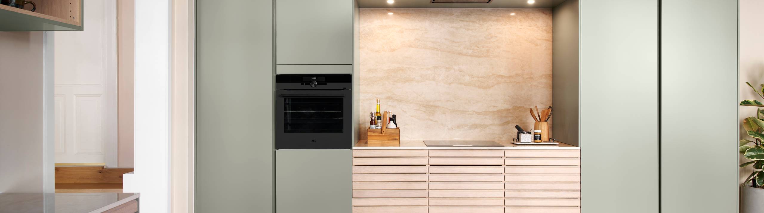 grebsfrie grønne køkkenet Highline Salvie med indfræsede greb i lågerne fra INVITA kombineret med med af egetræskøkken Ikon med håndsorterede lameller i massiv eg.