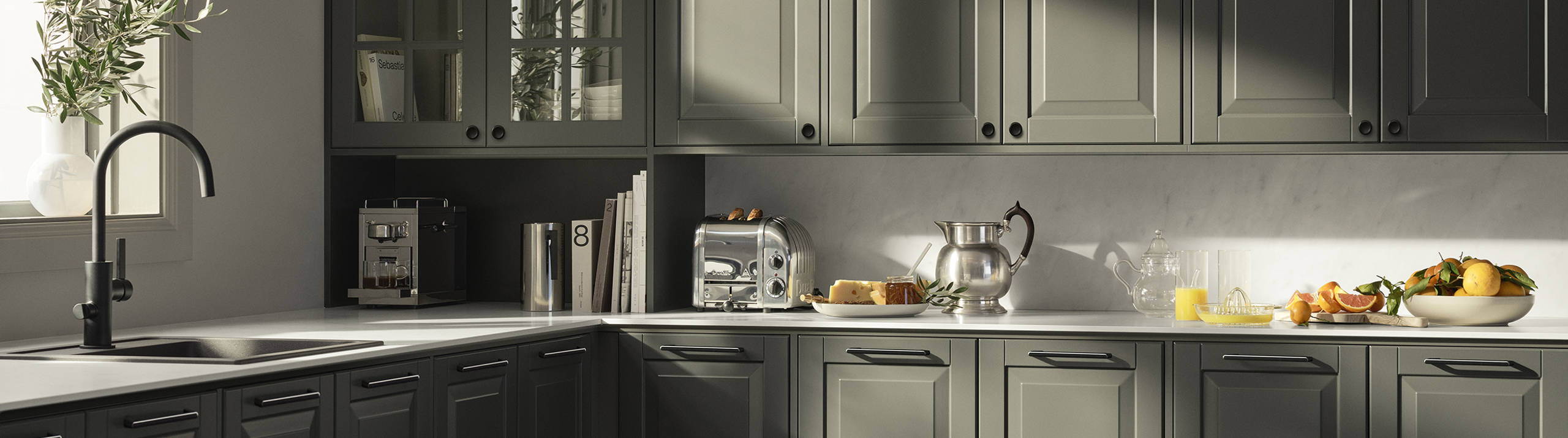 Mørkegrønt landkøkken Nordic Oliven fra INVITA med fyldningslåger, sort håndtag, vitrineskab med sprosselåger og hvid marmor laminatbordplade