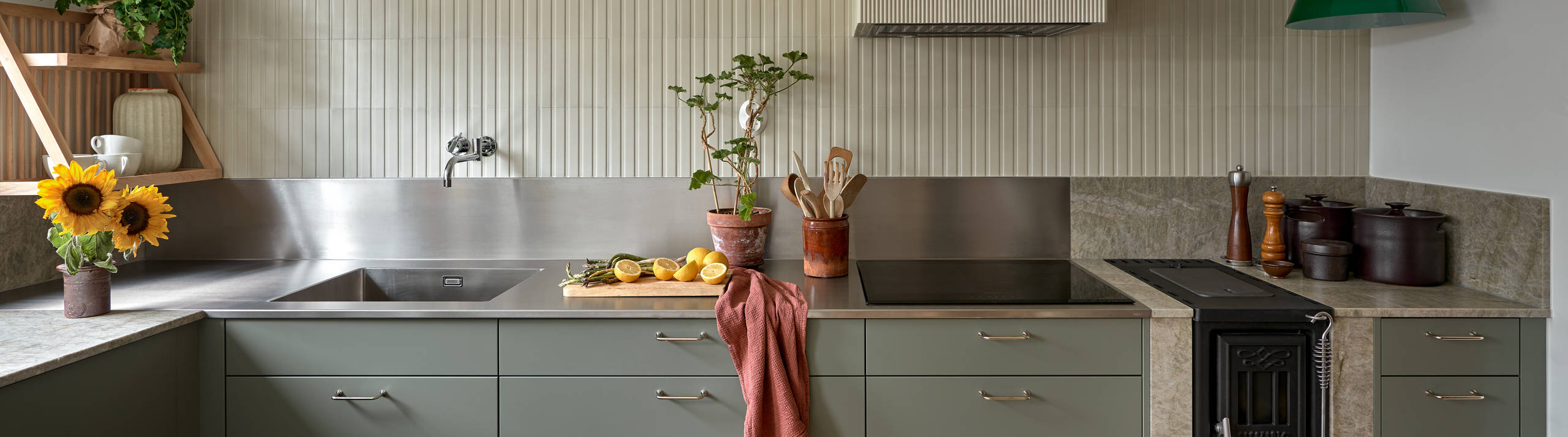 Gröna köket Arkitekt plus i kulören Tall med en vedspis och bänkskiva i kvartsit