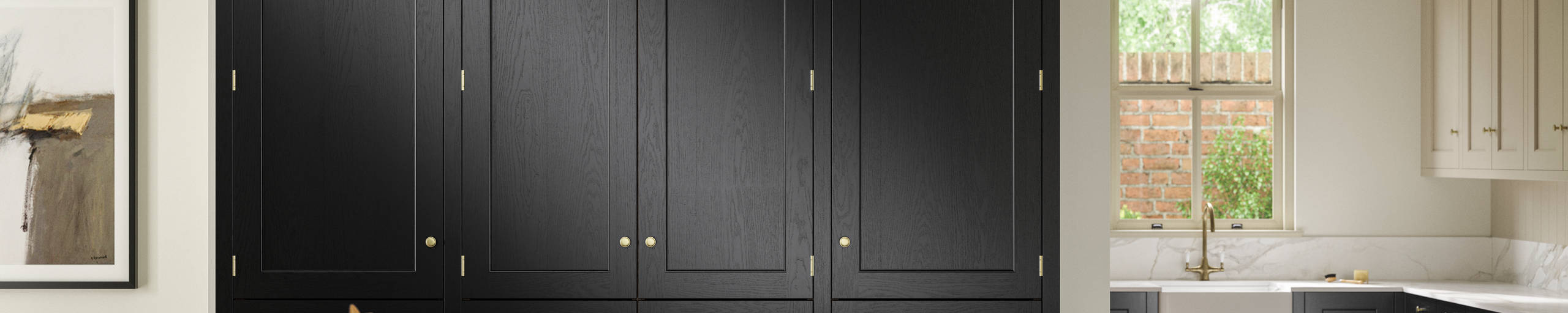 View over kitchen island in Traditional Shaker-style tactile woodgrain Ludlow Sumi Black kitchen with tall cabinets, brass accessories, marbled white and grey worktop, white ceramic sink and brass tap.