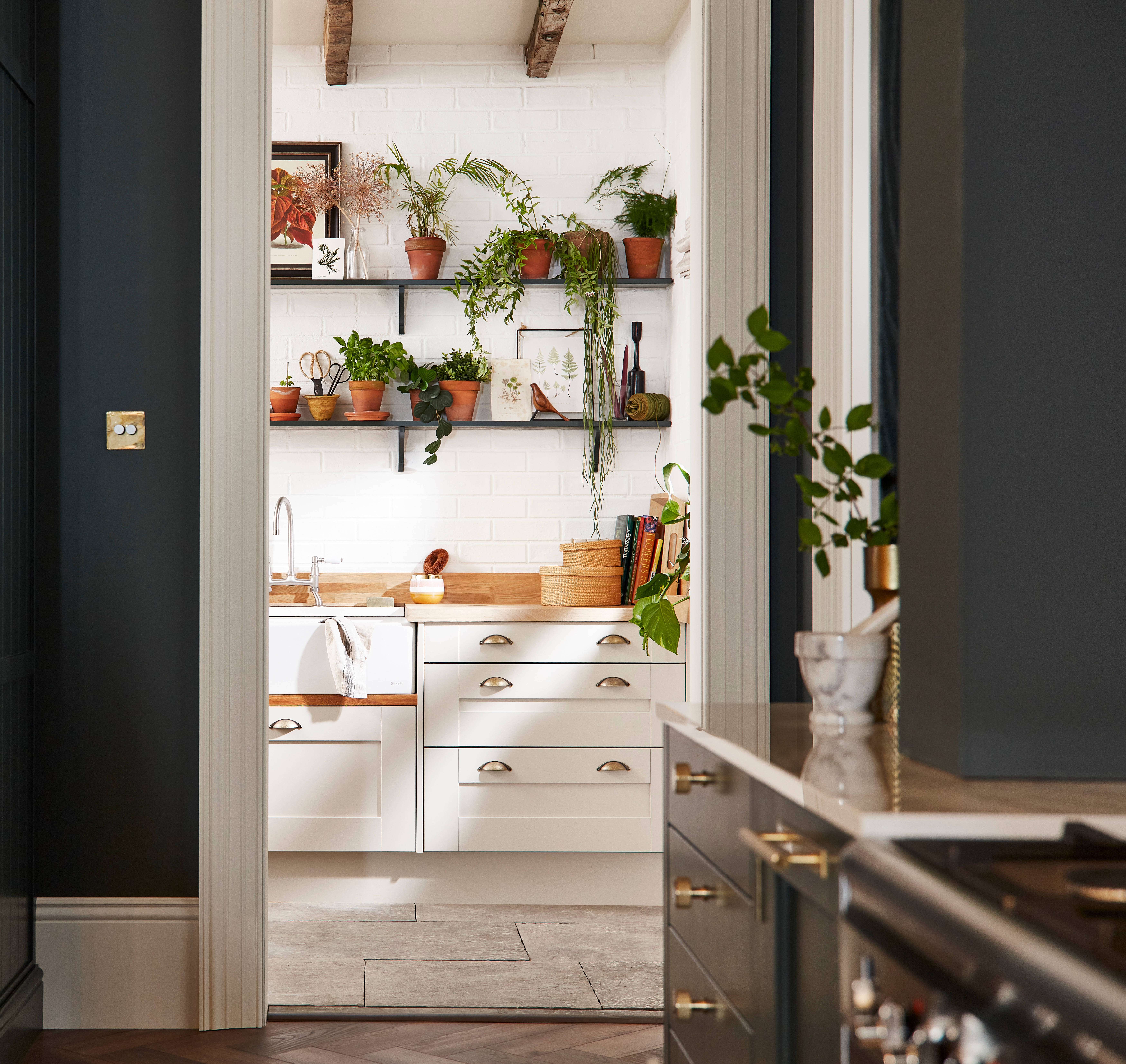 Ludlow, a traditional Shaker-style kitchen range in the shade Arboretum Green combined with a white utility room next door.