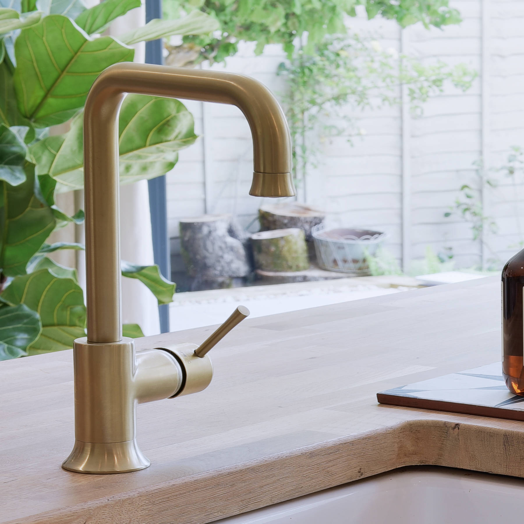 Close-up of Caple Belfast Ceramic sink which adds a rustic charm to the kitchen island. Paired with a wood worktop and brass tap.