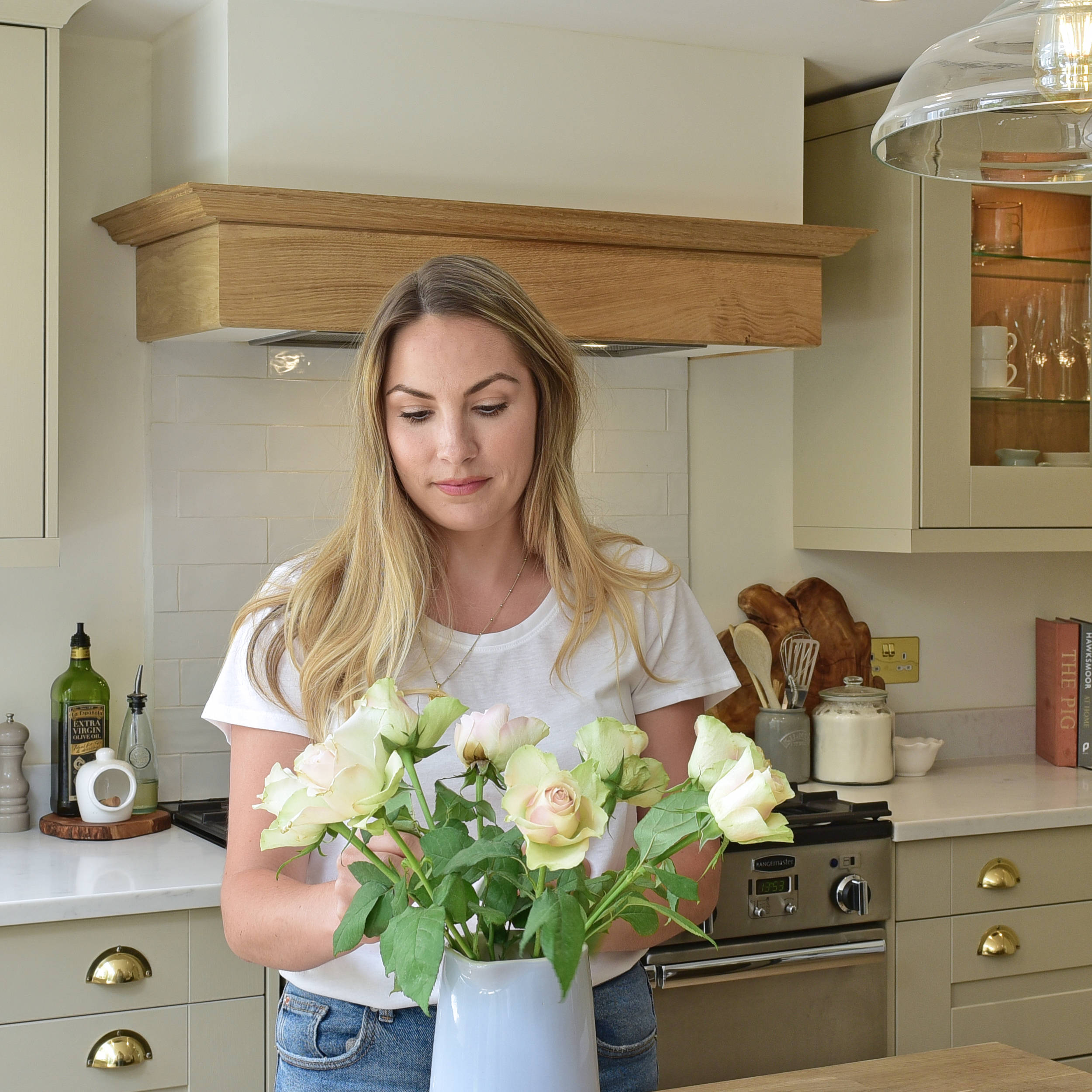 Magnet kitchen customer Leanne placing roses in a case on the kitchen island counter in her country cottage.